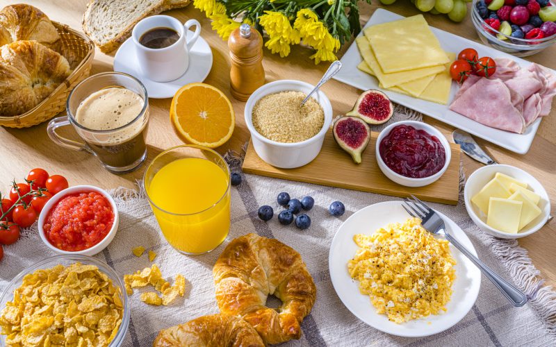 Healthy breakfast served with scrambled eggs, coffee, juice, croissants and fruits